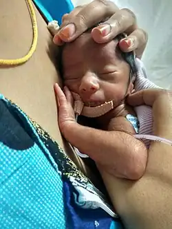 Mother uses the common skin to skin technique with her infant.