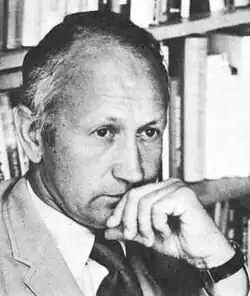 Photo portrait of a man looking concerned, with his head resting on his hand.