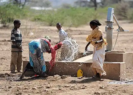 Children play by a newly installed hand pump in the village of Jedane.