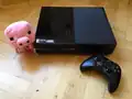 A pig plush next to an Xbox One.