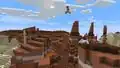 Sunny using a wind charge to jump across a badlands biome.