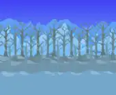 Leafless forest blocking snowy mountains with evergreens.