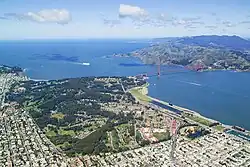 Aerial view of the Golden Gate Bridge connecting the wooded Presidio to the hilly Marin Headlands