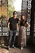 A man wearing a T-shirt and jeans and a woman wearing black T-shirt and white long skirt