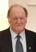 Head and shoulders of Bill Sheat smiling and dressed in a dark suit