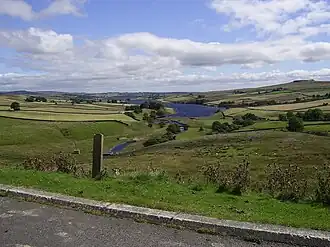 A view over a wide valley with a lake in the middle distance