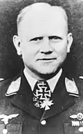 Black-and-white portrait of a man wearing a military uniform with various military decoration displayed at his neck.