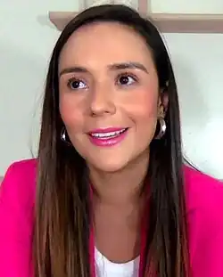 head and shoulders screenshot of caucasian female with long straight hair, around 40 years old