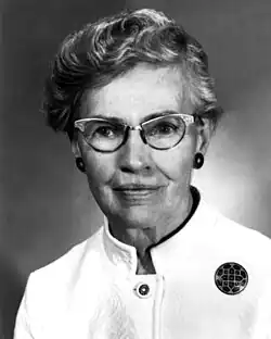 A white woman with short greying hair, wearing glasses