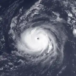 A powerful hurricane over the central Atlantic Ocean to the south-southeast of Bermuda, with a tightly wound cloud pattern around a clear eye