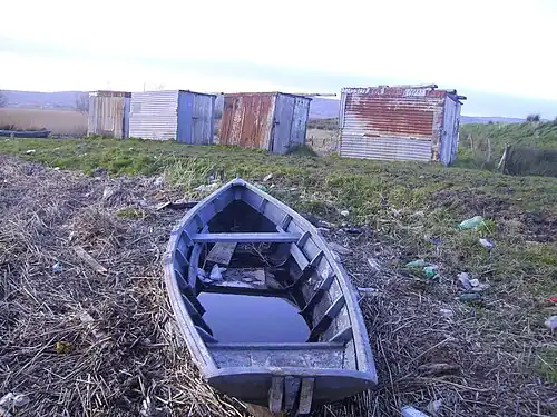 A gandelow used by the fishermen of Coonagh, with fishermens' cabins in the background