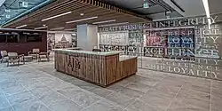 A wooden desk emblazoned with the Texas A&M logo situated next to a coffee table and chairs, and a mirrored wall with Texas A&M values printed across it.