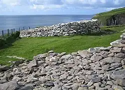 The fence marks the line of the top of the cliffs showing where parts of this promontory fort have fallen into the sea.
