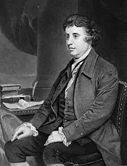 Black-and-white portrait of a man in a formal attire sitting next to a desk