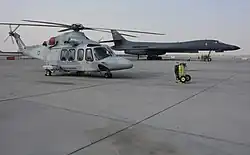 A Qatar Emiri Air Force AW139 and a US Air Force B-1B Lancer on the flight-line at Al Udeid Air Base during 2016.