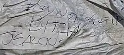 A wrinkled piece of white paper with the words "I'm not stupid bitch jealous" scrawled on them in ballpoint pen