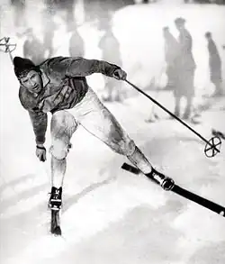 Johan Grøttumsbråten skiing on snow with the silhouettes of seven skiers in the background. Image is in black and white.