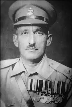 A black and white photograph (shoulder up) of an army officer wearing his uniform, medals and hat.
