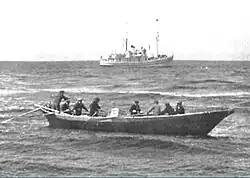 USFS Penguin (background) at anchor in the Bering Sea in 1939 while she unloads off St. George Island in the Pribilof Islands.
