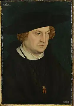 Middle-aged man in black, with a large black hat and light brown hair.