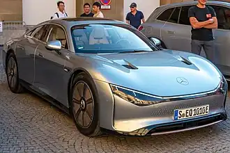 A front-three quarters view of a silver Mercedes-Benz. Pronounced fender hunches encase low-profile Bridgestone tyres, which shod 20 inch magnesium rims. A low-slung hood with a Mercedes-Benz sticker plastered on top and a light bar with low-profile headlights comprise the front of the concept.