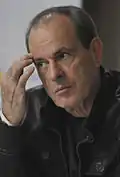 A man is wearing a black jacket and is facing left