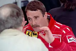 Nigel Mansell in racing outfit talking to another man