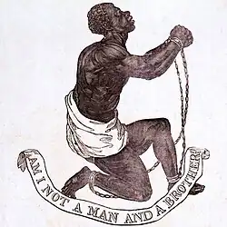 A black man with shackles around their wrists and ankles is kneeling to the right. An inscription at the bottom reads ""Am I not a man and a brother?"
