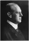 Black and white photograph of Ernest Fox Nichols from a side view, with short hair, wearing a suit and tie.