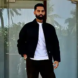 A color photograph of a bearded man wearing all black clothes