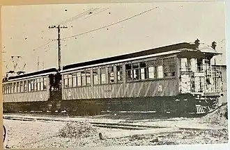 Two electric railway cars, one with a pantograph, at the end of a track
