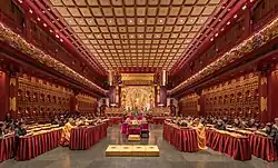 Praying monks and nuns in the temple with laypeople seated behind them in the Hundred Dragon Hall