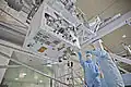 A view of the RRM on the underside of the LMC in the SSPF with technicians for scale