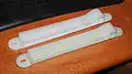 An Alfa Romeo Alfetta GTV hood prop rod guide - The part shown on top is a reproduction of the original below.