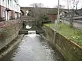 River Brent at Brent Cross. The Ordnance Survey 1:50,000 scale mapping shows a sea of dark green here as the A406 North Circular Road and the A41 Hendon Way meet at the Brent Cross Flyover. A small weir impounds a head of water as the river flows down towards the Brent Reservoir.
