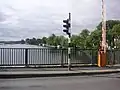 a view from a bridge through metal railings to the river below
