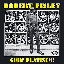 A black-and-white photo of Finley standing in front of rows of hubcaps