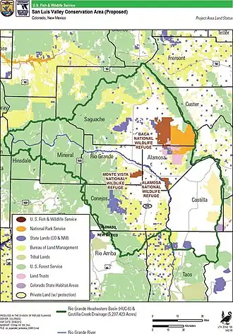 Map of a wide alpine valley showing federal ownership of forests and scrubland in highlands surrounding a central area of privately owned land. A national park and several wildlife refuges and private lands subject to conservation easements are depicted. A river flows through it.
