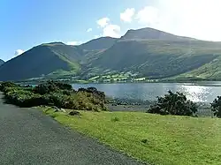 Lush hills beyond a long, narrow lake.