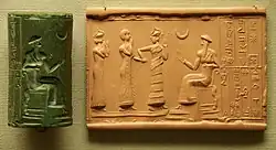 Sumerian cylinder seal and impression, dated c. 2100 BC, of Ḫašḫamer, ensi (governor) of Iškun-Sin c. 2100 BC. The seated figure is probably king Ur-Nammu, bestowing the governorship on Ḫašḫamer, who is led before him by Lamma (protective goddess).[349]