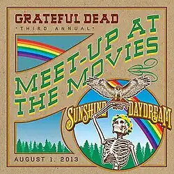 A skeleton with a flower headdress holds aloft a hawk with outspread wings. In the background is a forest, with a rainbow in the sky.