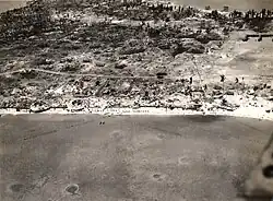 Aerial view of Betio, Tarawa Atoll, 24 November 1943, looking north toward "The Pocket", the last place of Japanese resistance. An emplacement just onshore with two 12.7&nbsp;mm anti-aircraft guns is visible near the left edge of the photograph.