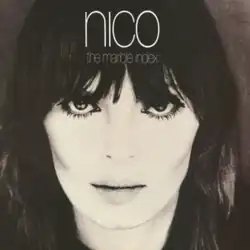 Close-up, black-and-white photograph of a dark haired woman, looking at the camera with a deep sight