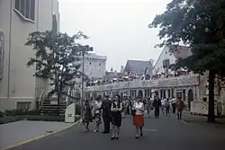A crowded street with low-rise buildings and trees.