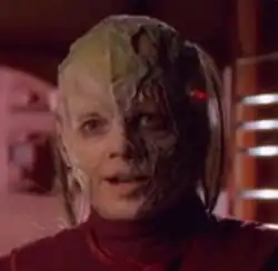 A humanoid with decaying skins looks toward the camera.