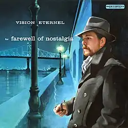 man wearing an overcoat, scarf, and fedora hat, holding a tobacco pipe at night on the waterfront.