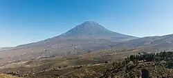 A conical mountain rises above a brown slope